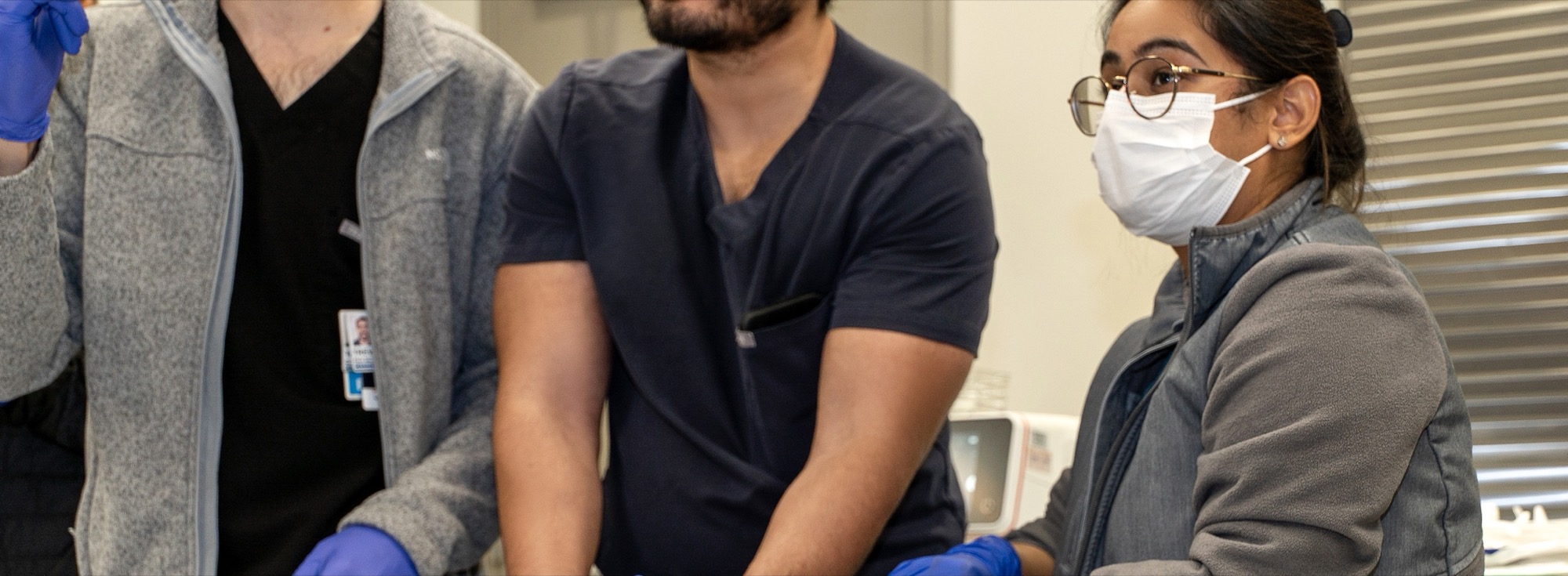 Close-up of fellows collaborating around the procedure table
