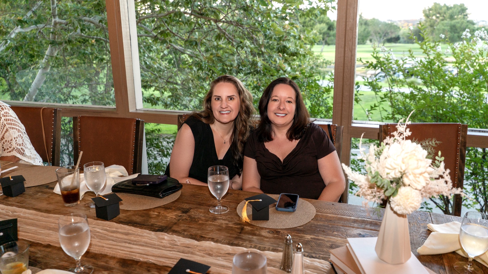 Two guests smiling at their table with the golf course view behind them