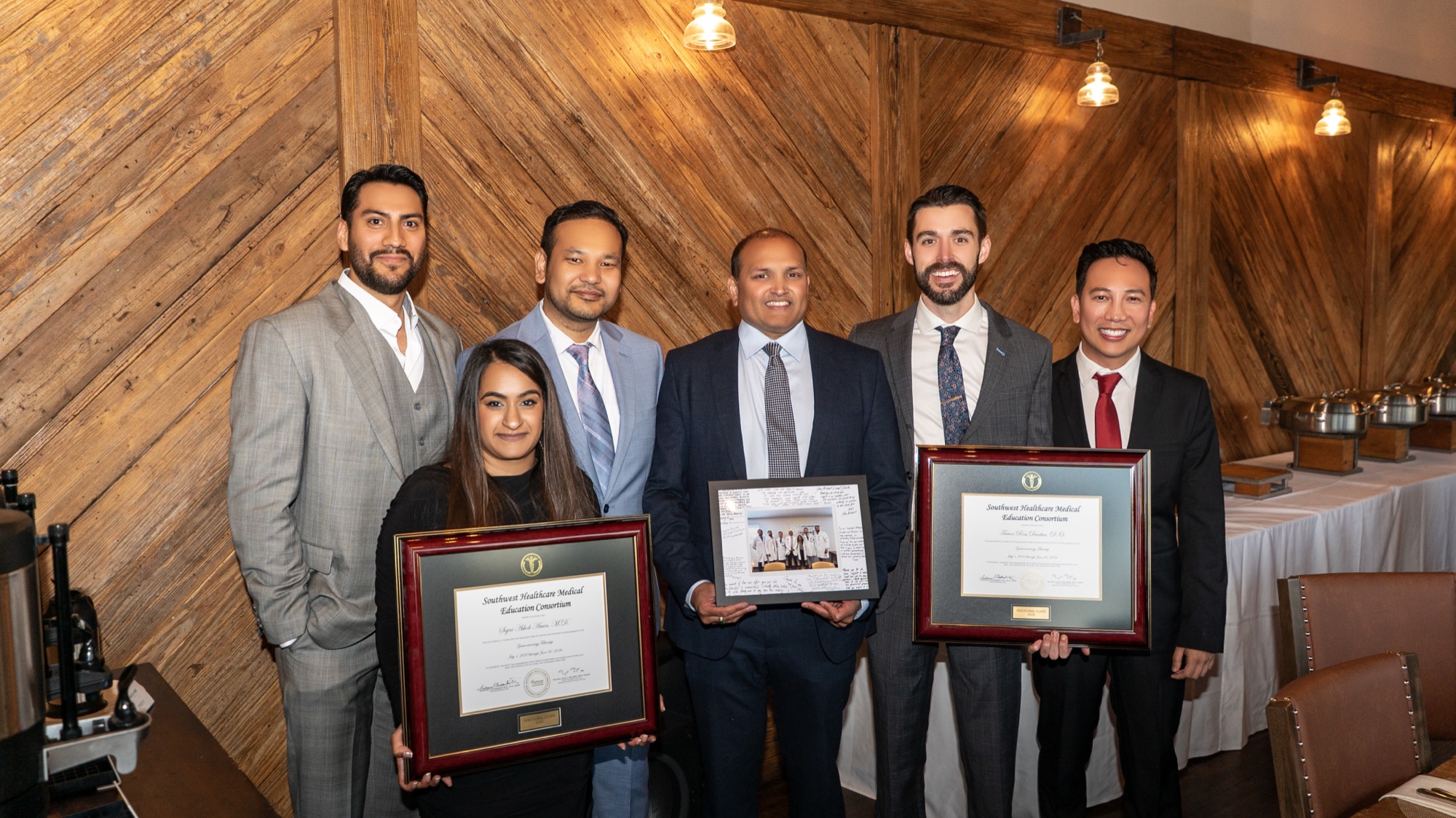 Dr. Amin and Dr. Dunbar with mentors holding a signed keepsake and certificates
