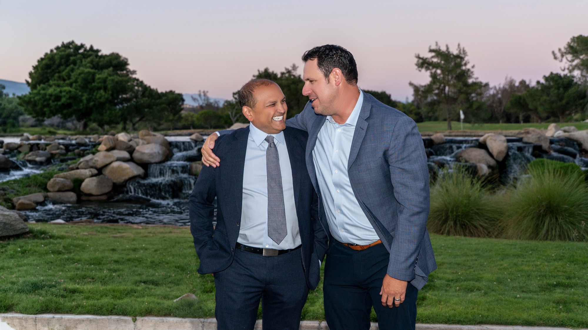 Dr. Veluvolu and a colleague sharing a laugh by the waterfall at dusk