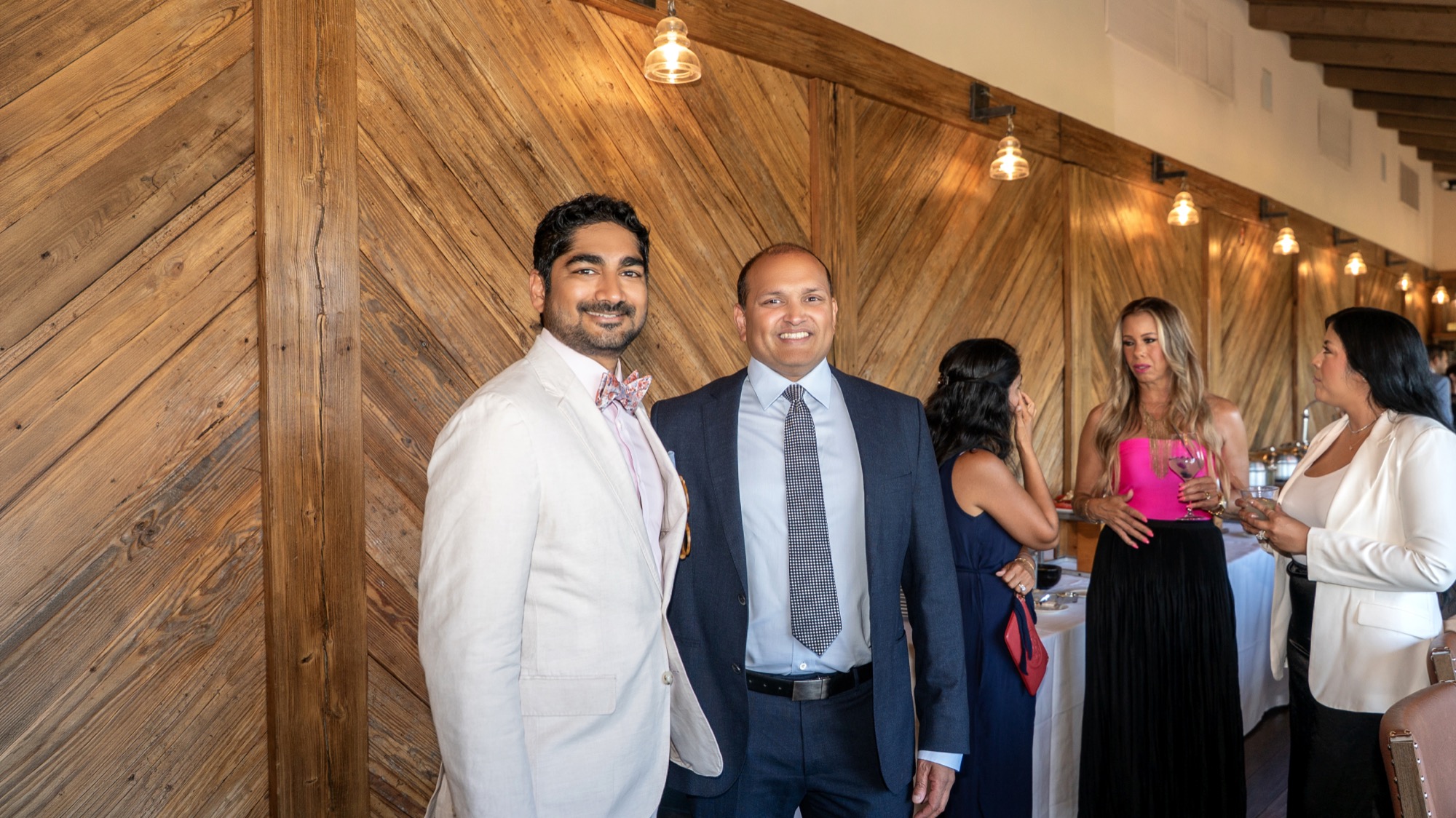 Dr. Amin's husband and a Trinity MSG physician posing by the wood-paneled wall