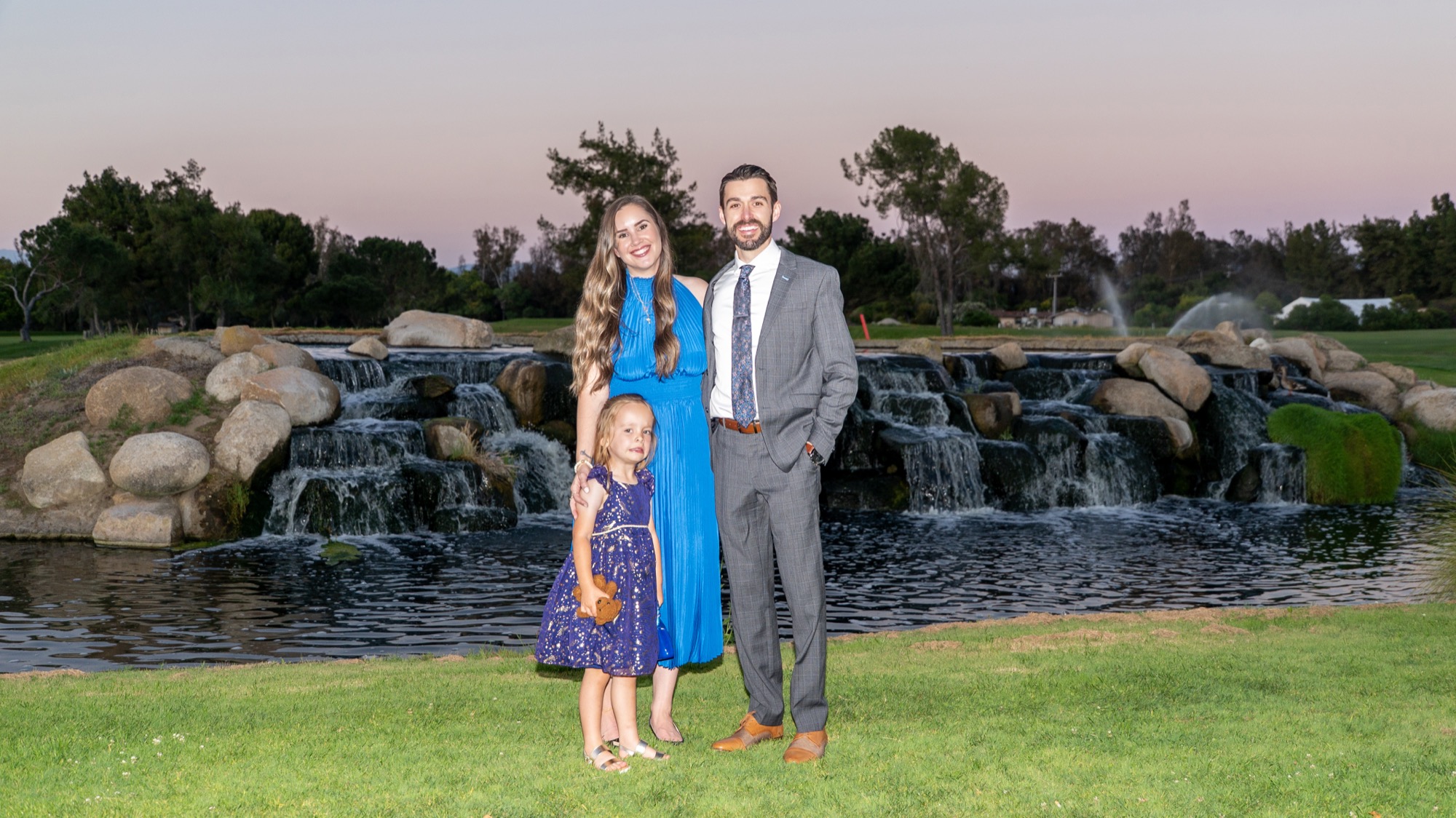 Dr. Trevor Dunbar with his wife and daughter by the waterfall at dusk