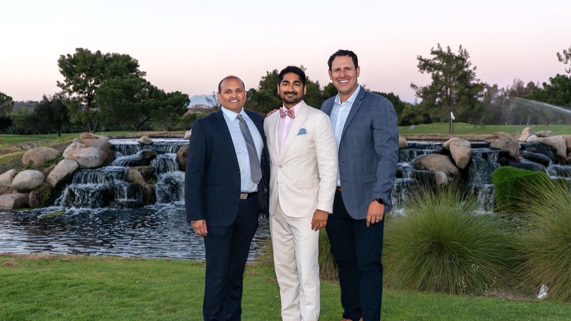 Dr. Veluvolu, Dr. Amin's husband, and a Trinity MSG physician by the waterfall at sunset