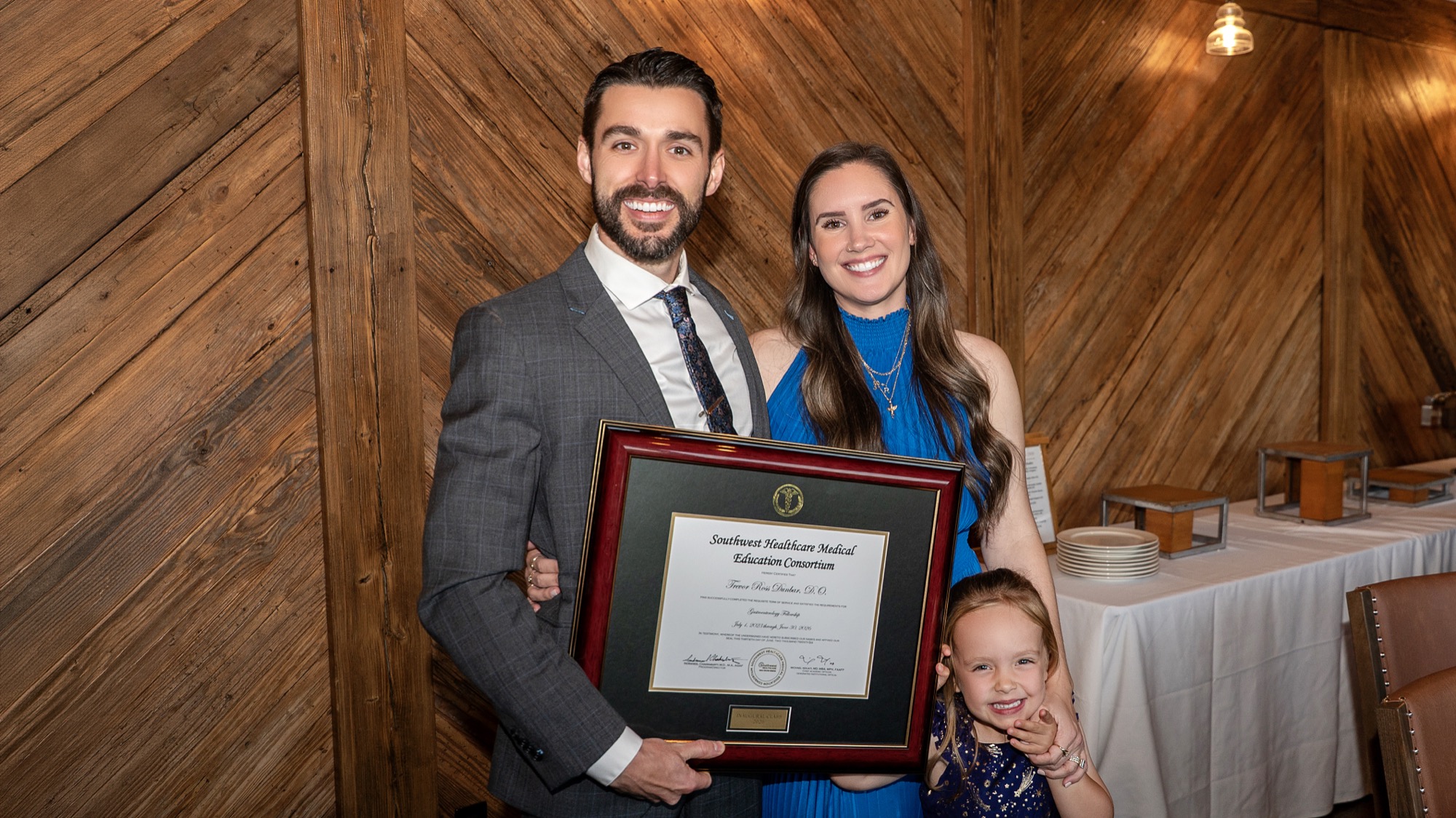 Dr. Trevor Dunbar with his wife and daughter holding his fellowship certificate