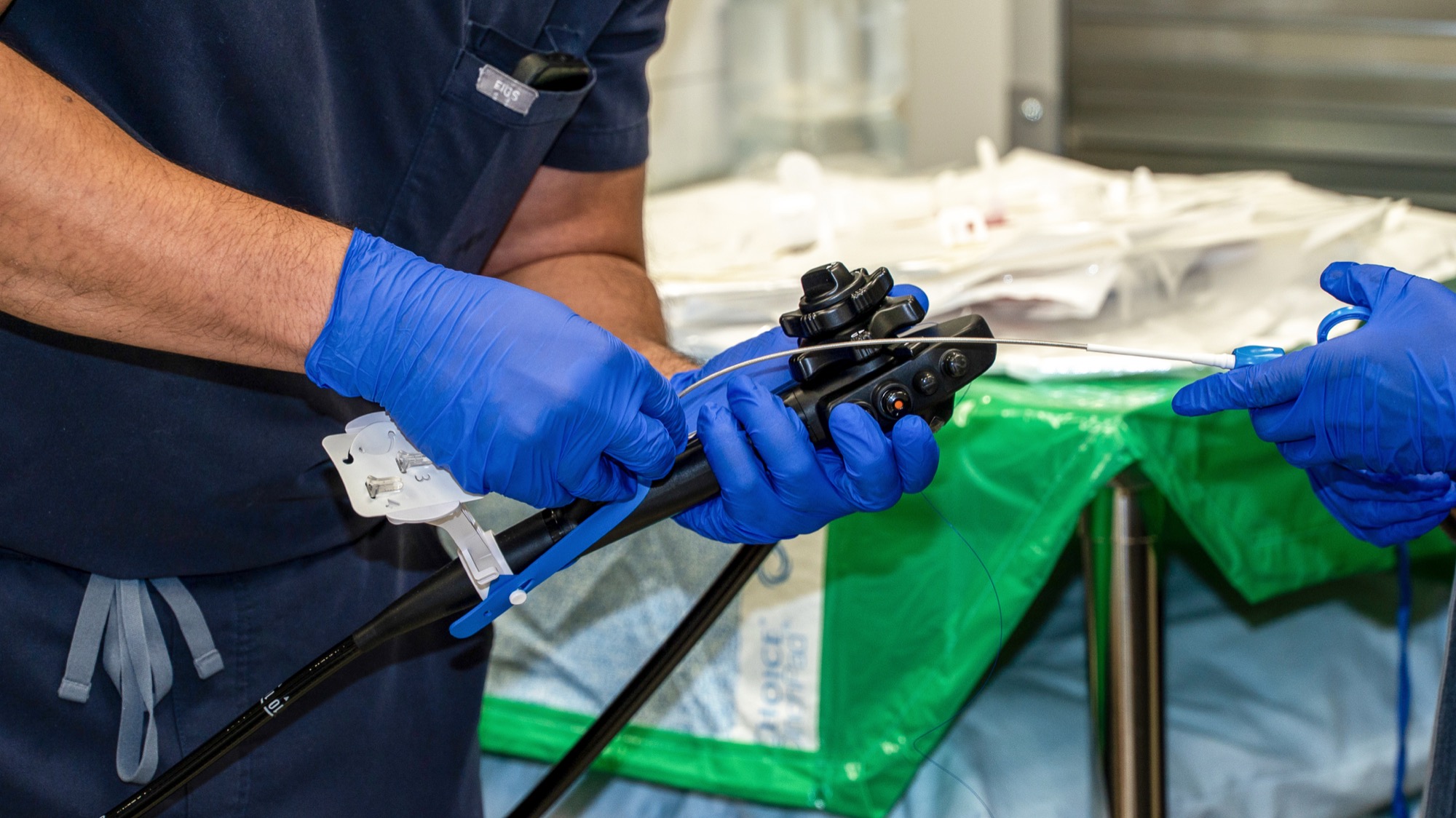 Close-up of gloved hands controlling the endoscope handle and accessory tool